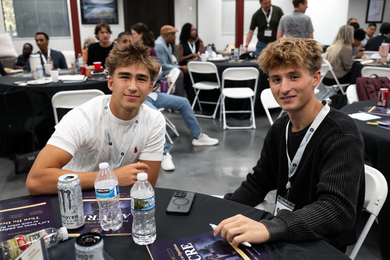 Young attendees following live deal conversations at the table